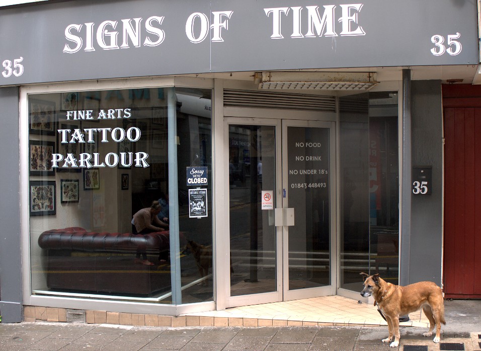 Signs of time Junk shop frontage with forlorn dog