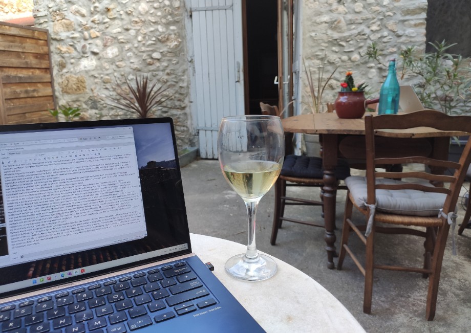 Experience Laptop with writing on screen, glass of white wine